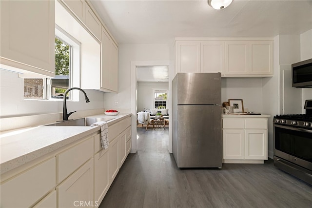 kitchen featuring dark wood-style floors, light countertops, white cabinetry, appliances with stainless steel finishes, and a sink