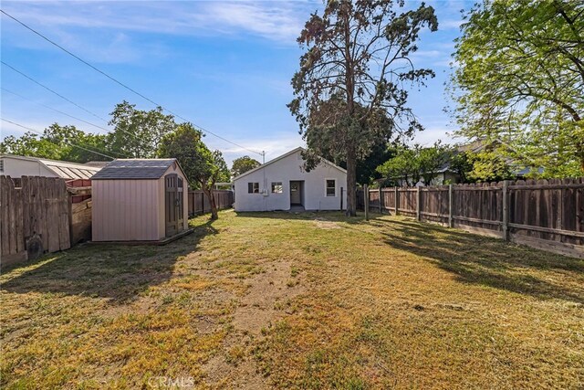view of yard with a shed, a fenced backyard, and an outdoor structure