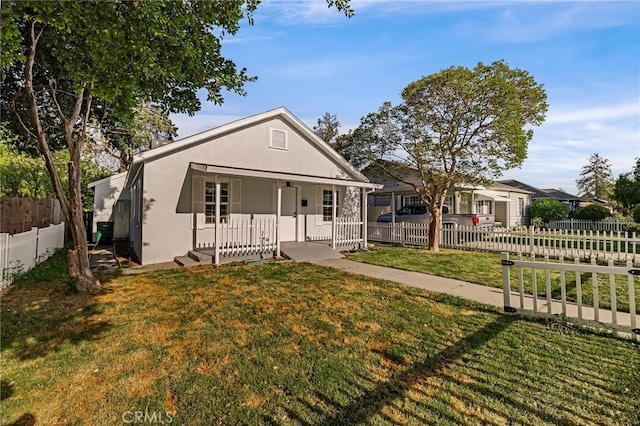 bungalow-style house with a porch, stucco siding, a front lawn, and a fenced front yard