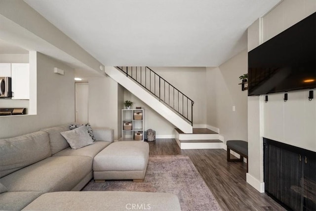 living room with stairs, dark wood-style floors, and baseboards