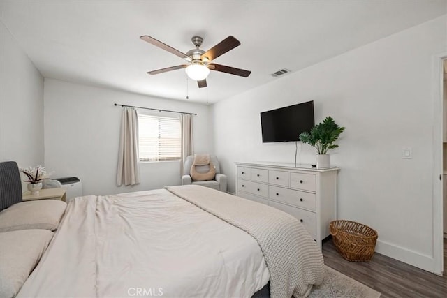 bedroom with wood finished floors, ceiling fan, baseboards, and visible vents