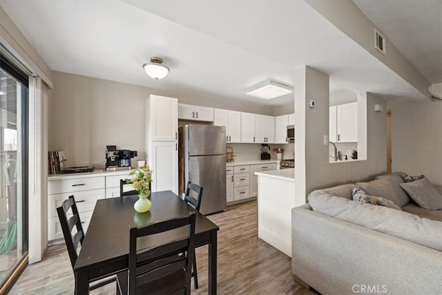 kitchen with white cabinets, open floor plan, light wood-style flooring, and stainless steel appliances