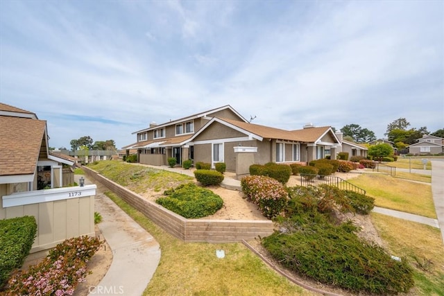 view of front of home featuring stucco siding, fence, and a front lawn