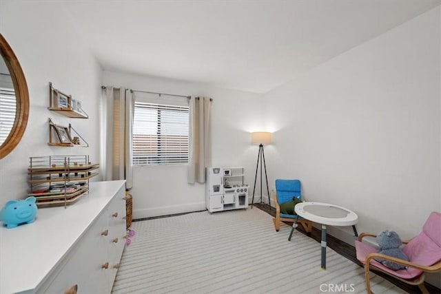 living area featuring light carpet and baseboards