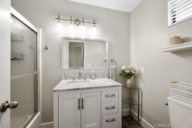 full bathroom with shower / bath combination with glass door, vanity, baseboards, toilet, and wood finished floors