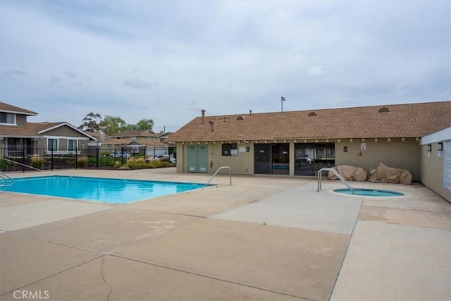 pool with fence, a patio, and a community hot tub