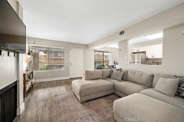 living area with visible vents, baseboards, and wood finished floors