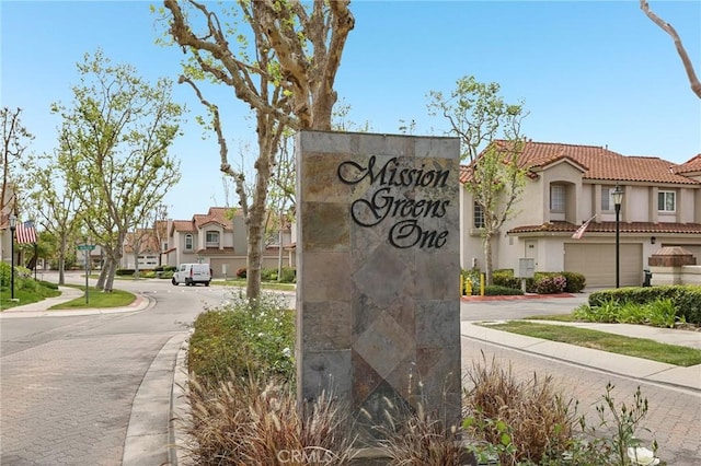 community / neighborhood sign with a residential view, a garage, and concrete driveway