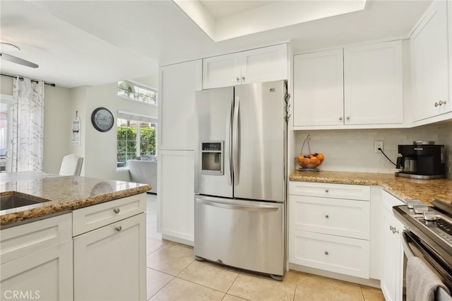 kitchen with light stone countertops, light tile patterned floors, white cabinetry, and appliances with stainless steel finishes