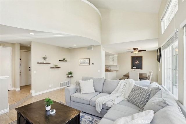 living area with visible vents, ceiling fan, a towering ceiling, and light tile patterned floors