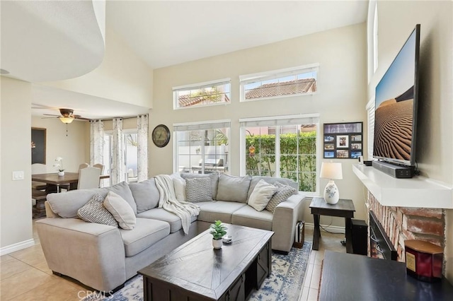 living area featuring light tile patterned floors, ceiling fan, a towering ceiling, and a healthy amount of sunlight