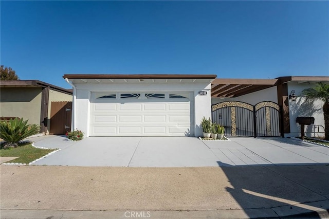 ranch-style home featuring stucco siding, fence, a gate, an attached garage, and driveway