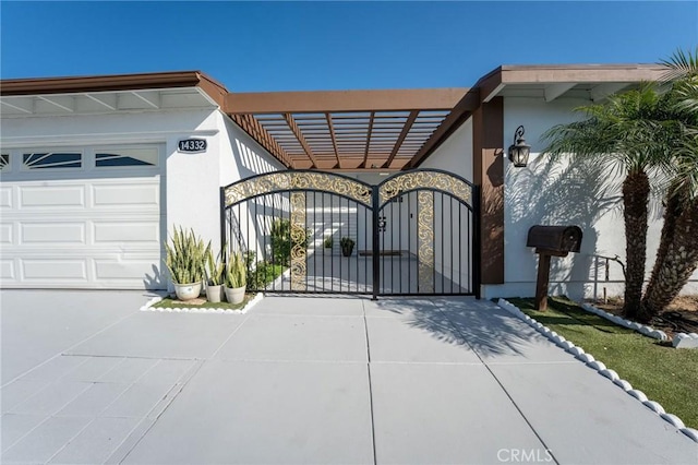 view of front of home with an attached garage, driveway, stucco siding, and a gate