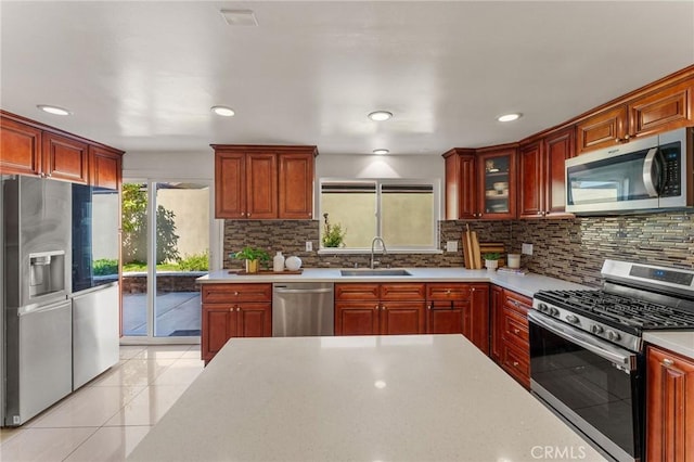 kitchen with stainless steel appliances, tasteful backsplash, light countertops, and a sink