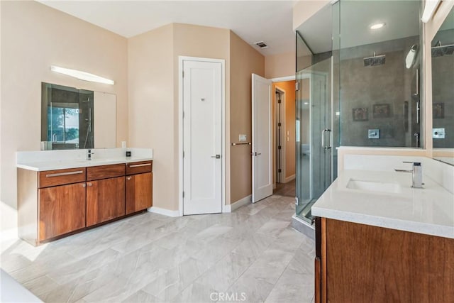 bathroom with visible vents, baseboards, a sink, a shower stall, and two vanities