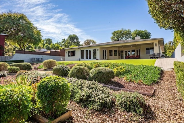 rear view of house with a patio area, stucco siding, and a chimney