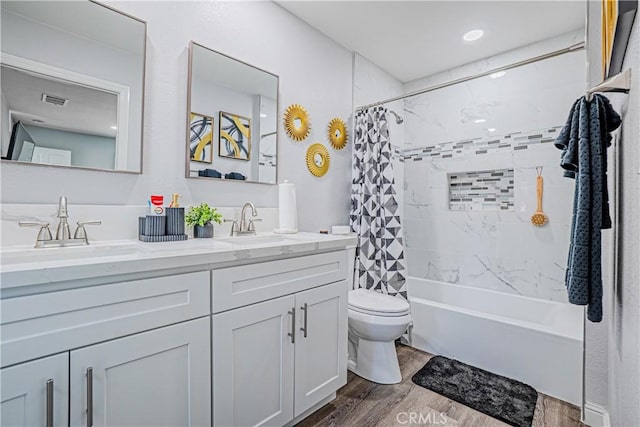 full bathroom featuring visible vents, toilet, wood finished floors, a sink, and double vanity