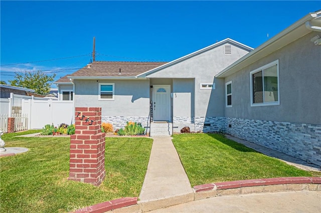 view of front of home with a front yard, fence, and stucco siding