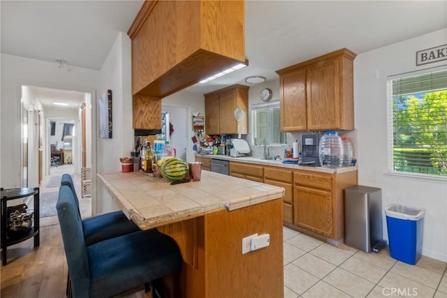 3110 Mckee Rd, Merced, CA 95340 - kitchen with tile counters, stainless steel dishwasher, a kitchen breakfast bar, a sink, and a peninsula