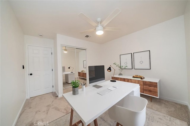 office featuring baseboards, visible vents, a ceiling fan, and light colored carpet