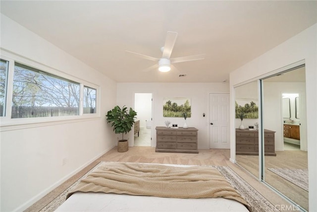 carpeted bedroom featuring ensuite bathroom, visible vents, baseboards, a closet, and ceiling fan