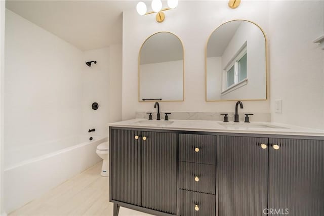bathroom featuring double vanity, toilet, wood finished floors, and a sink