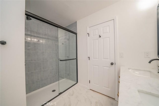 bathroom with a tile shower, marble finish floor, and a sink