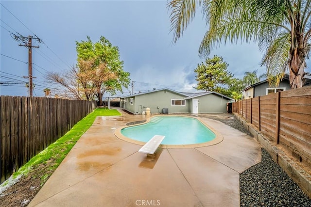 view of pool with a fenced backyard, a fenced in pool, a diving board, and a patio