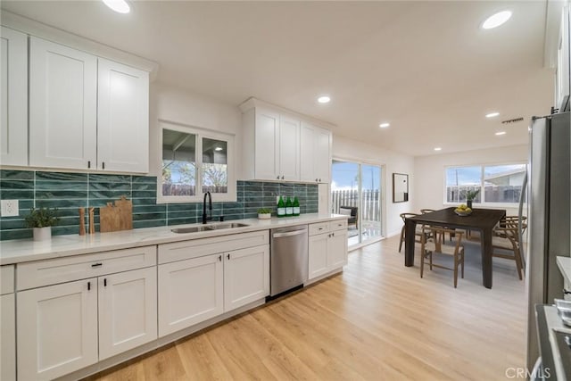 kitchen with dishwasher, light wood-type flooring, white cabinetry, and a sink