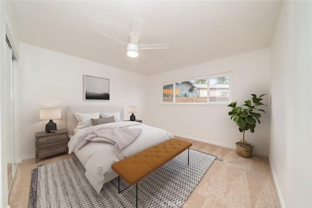 bedroom featuring ceiling fan, light carpet, a closet, and baseboards