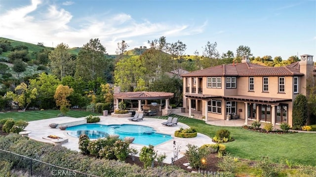 rear view of property with a chimney, stucco siding, a yard, a gazebo, and a patio