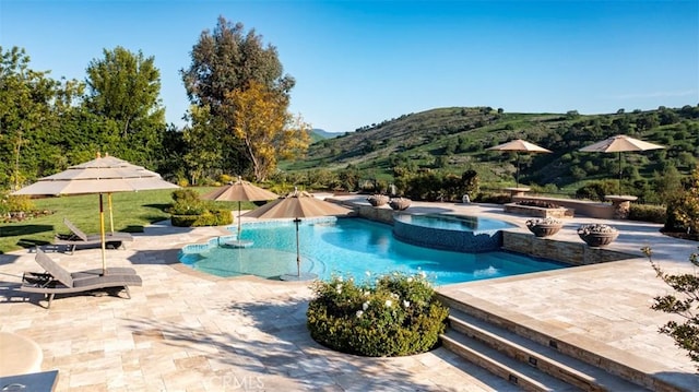 view of pool with a mountain view, a patio, and a pool with connected hot tub