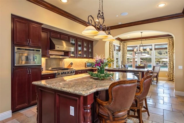 kitchen featuring stone tile flooring, tasteful backsplash, range hood, and baseboards