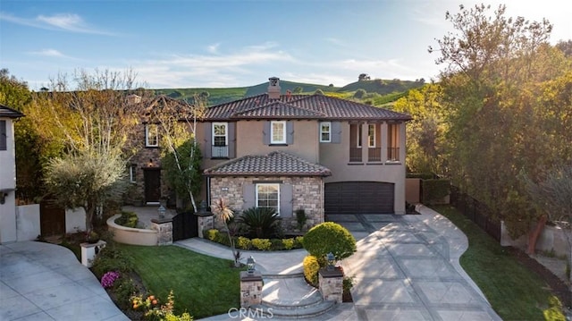 mediterranean / spanish-style house with driveway, stone siding, a chimney, an attached garage, and stucco siding