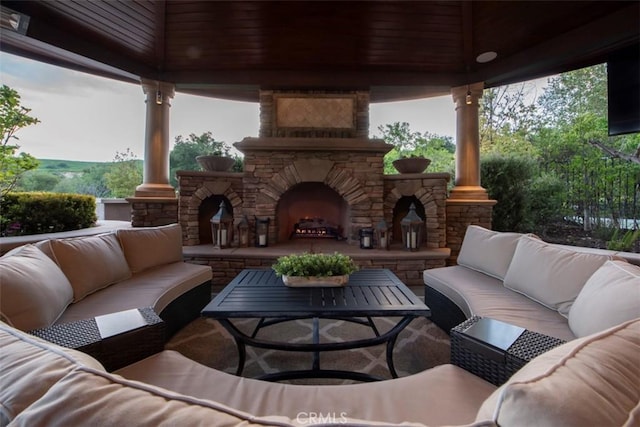 view of patio with an outdoor living space with a fireplace and a gazebo