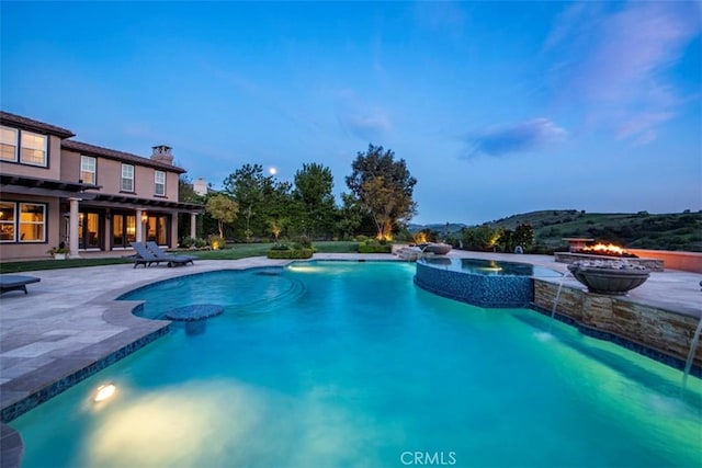 outdoor pool featuring a fire pit, an in ground hot tub, and a patio area