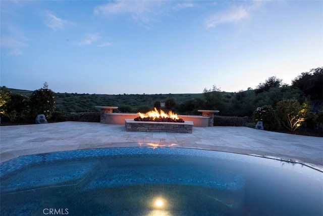 pool with a fire pit and a patio area
