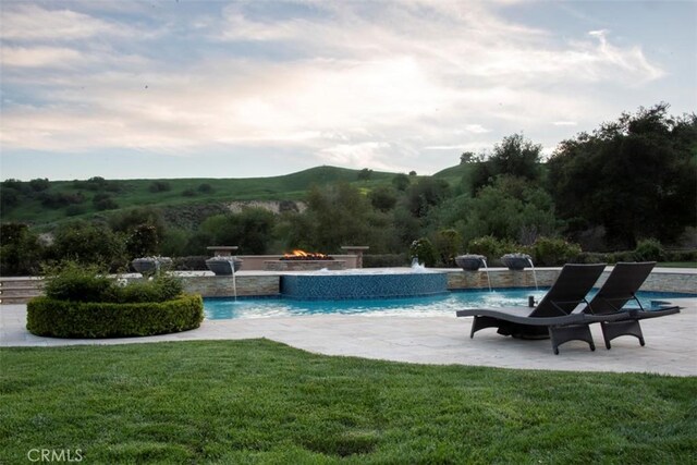 outdoor pool featuring a fire pit, a yard, and a patio area