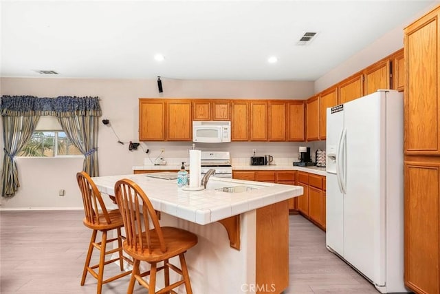 39356 Nicole Dr, Palmdale, CA 93551 - kitchen with recessed lighting, white appliances, light wood-style flooring, visible vents, and a center island with sink
