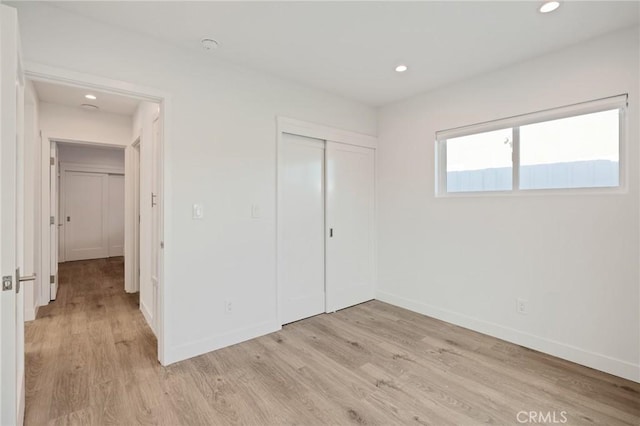 unfurnished bedroom featuring light wood-type flooring, baseboards, recessed lighting, and a closet