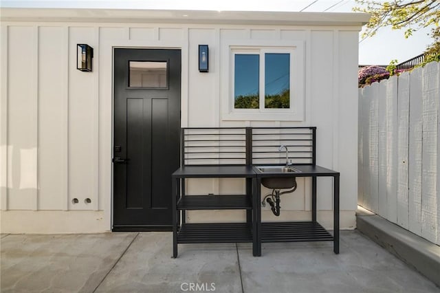 view of exterior entry with board and batten siding and fence