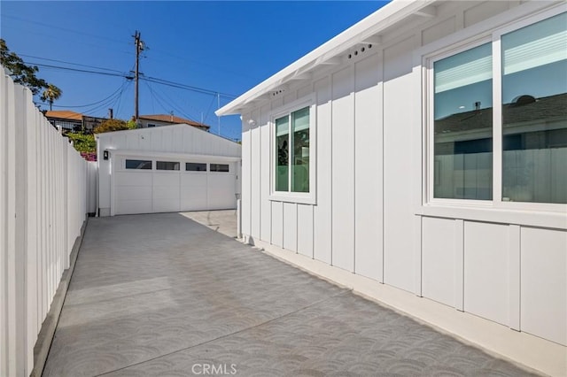 view of side of home with board and batten siding, fence, a garage, and an outdoor structure