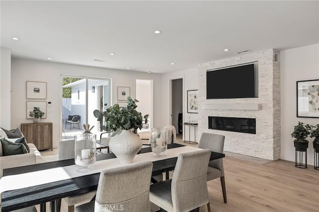 dining space with recessed lighting, light wood-style flooring, visible vents, and a stone fireplace