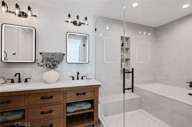 bathroom with a bath, walk in shower, double vanity, and a sink