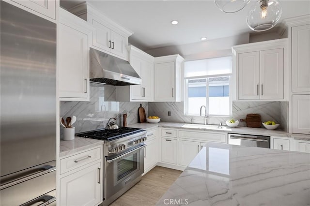 kitchen featuring recessed lighting, premium appliances, under cabinet range hood, a sink, and white cabinetry