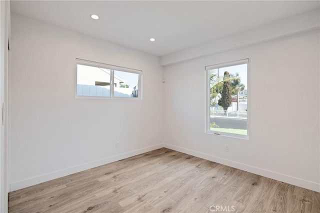 spare room with recessed lighting, light wood-style flooring, a wealth of natural light, and baseboards