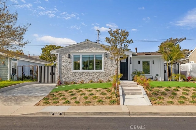 view of front of house with stone siding, fence, and a gate