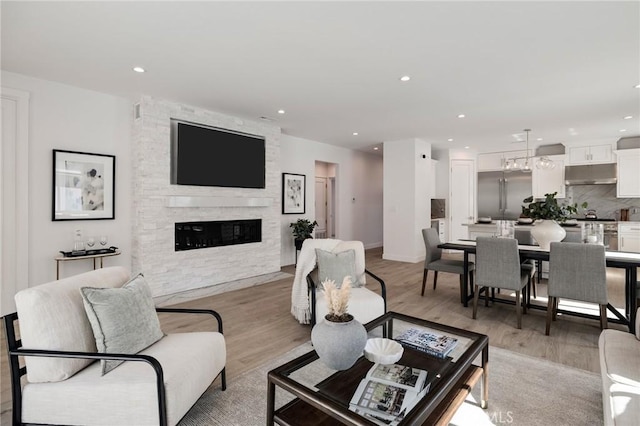 living area with recessed lighting, light wood finished floors, and a fireplace