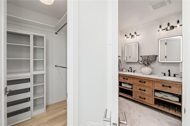 bathroom with double vanity, a spacious closet, and a sink