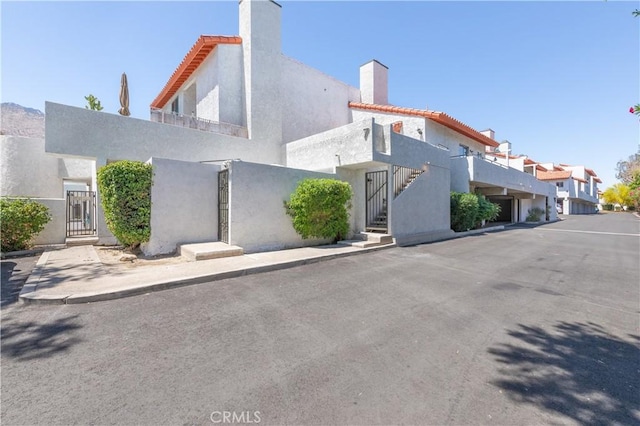 280 S Avenida Caballeros Unit 271, Palm Springs, CA 92262 - view of asphalt road with a gate, sidewalks, a residential view, and curbs